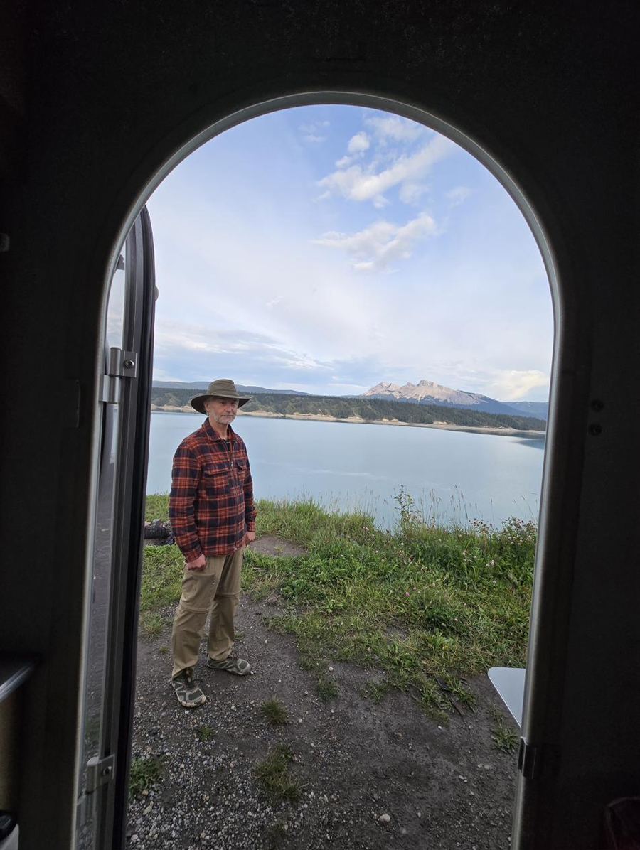 Todd standing in an open doorway, looking out over a mountain lake