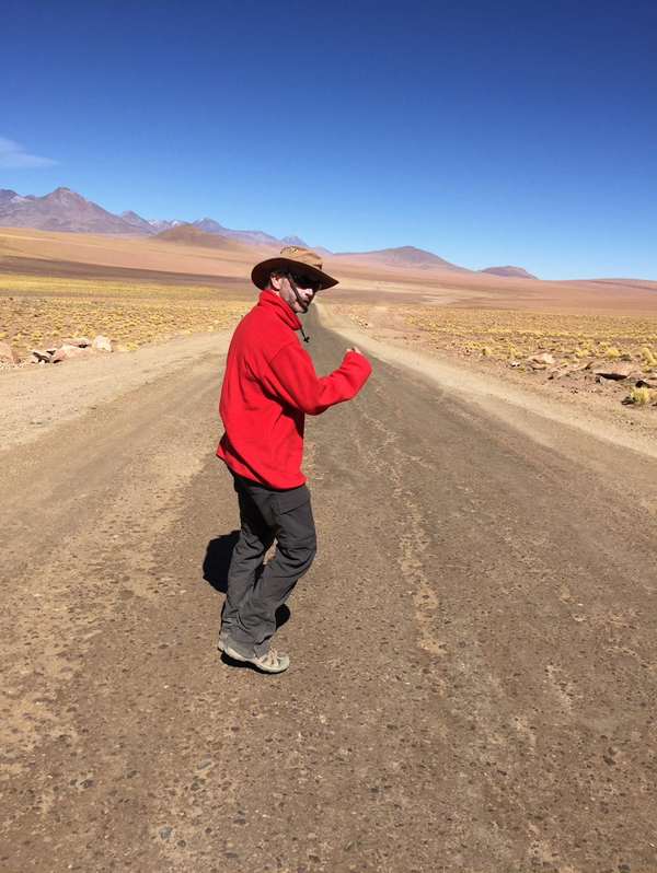 Todd walking down a desert road, glancing back over his shoulder