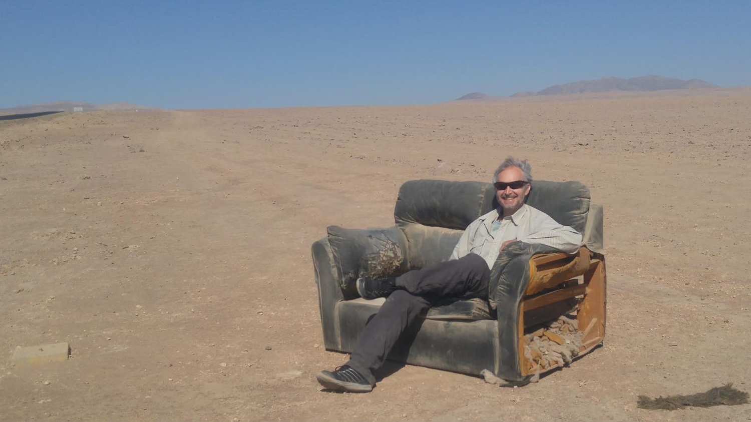 Todd relaxing in a worn armchair in the middle of a vast desert