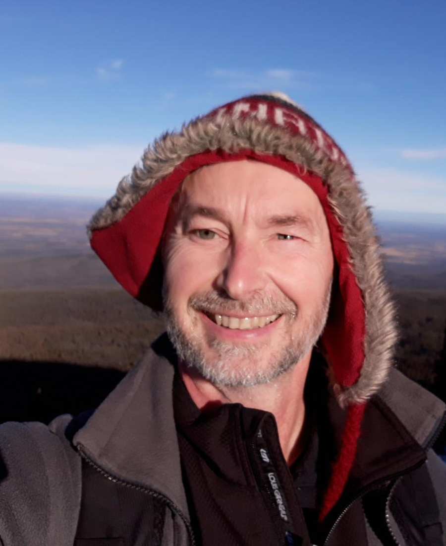 Todd smiling outdoors on a mountain ridge